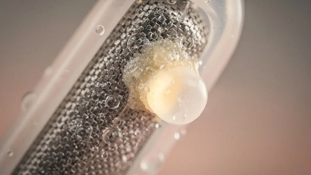 Macro d’une fine condensation sur un embout d’appareil auditif, suggérant l’humidité piégée dans un conduit étroit.